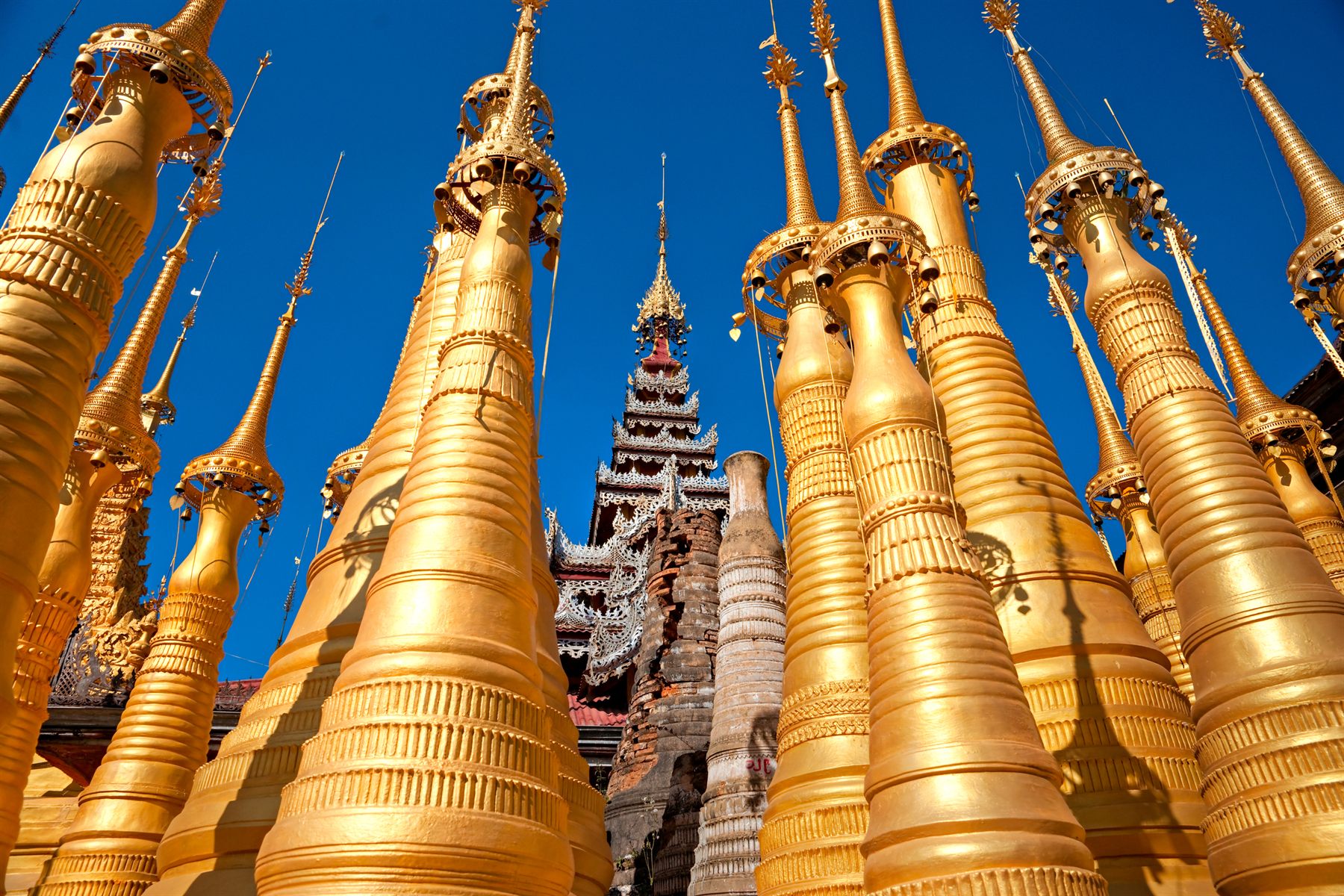 Gilded stupa spires against a deep blue sky, Myanmar